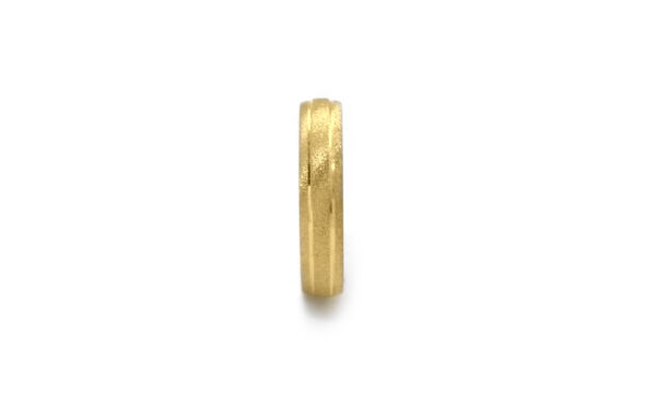 Wedding ring in solid gold with decorative lines.